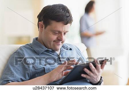 Stock Photo - Man with down syndrome using tablet. Fotosearch