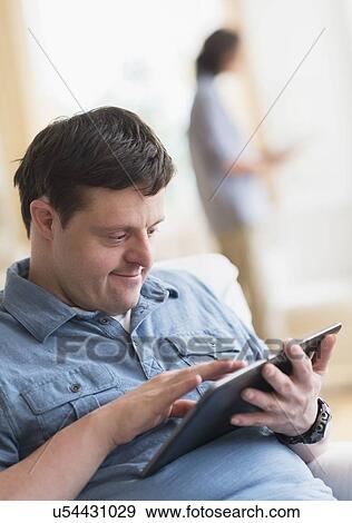 Man with down syndrome using tablet View Large Photo Image Stock Photo - Man with down syndrome using tablet. Fotosearch