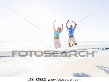 Mature couple jumping in sea with arms raised View Large Photo Image Stock Image - Mature couple jumping in sea with arms raised. Fotosearch