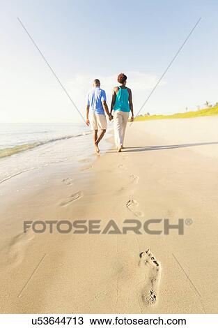 Stock Image - Mature couple walking on beach. Fotosearch