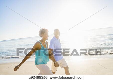 Stock Photograph - Mature couple walking on beach. Fotosearch