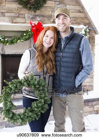Mid adult couple holding wreath View Large Photo Image Stock Photo - Mid adult couple holding wreath. Fotosearch