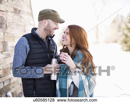 Mid adult couple looking face to face and having drink from vacuum flask View Large Photo Image Stock Photo - Mid adult couple looking face to face and having drink from vacuum flask. Fotosearch