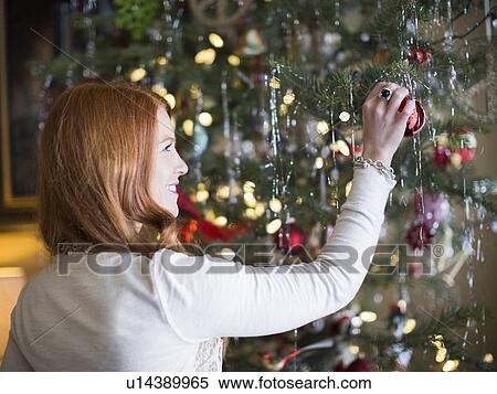Mid adult woman decorating Christmas tree View Large Photo Image Stock Photography - Mid adult woman decorating Christmas tree. Fotosearch