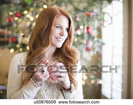 Stock Photo - Mid adult woman with coffee mug in christmas time. Fotosearch