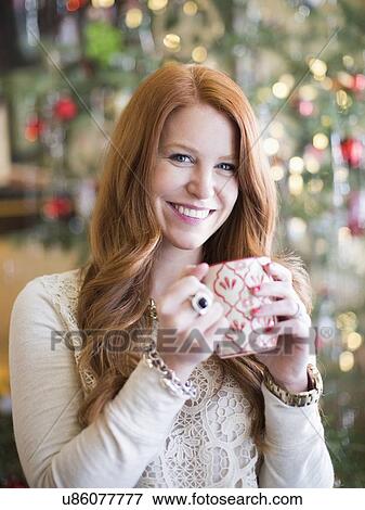 Stock Photo - Mid adult woman with coffee mug in christmas time. Fotosearch