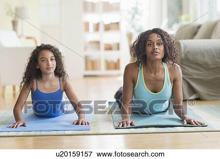 Mother and daughter (8-9) exercising in living room View Large Photo Image Stock Photo - Mother and daughter (8-9) exercising in living room. Fotosearch