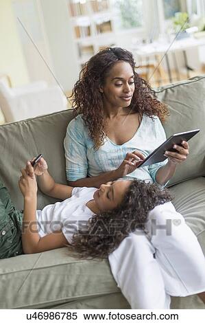 Mother and daughter (8-9) relaxing on sofa View Large Photo Image Stock Photography - Mother and daughter (8-9) relaxing on sofa. Fotosearch