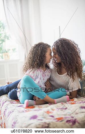Mother and daughter (8-9) rubbing noses on bed View Large Photo Image Stock Image - Mother and daughter (8-9) rubbing noses on bed. Fotosearch