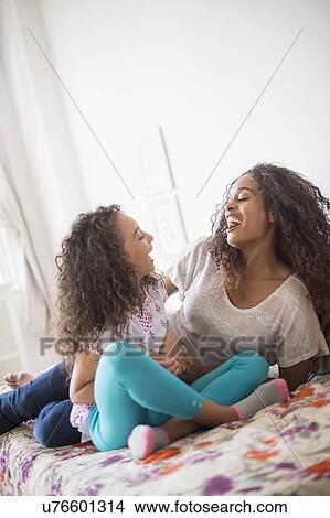 Mother and daughter (8-9) sitting on bed View Large Photo Image Picture - Mother and daughter (8-9) sitting on bed. Fotosearch