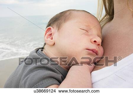 Picture - Mother holding newborn daughter on beach. Fotosearch