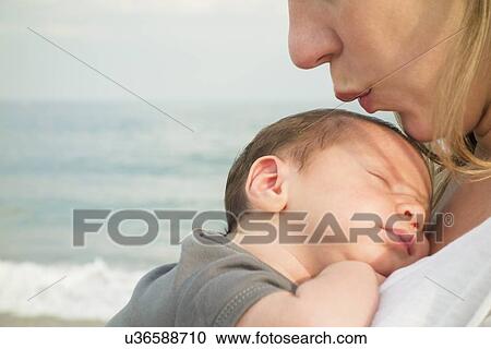 Stock Image - Mother holding newborn daughter on beach. Fotosearch