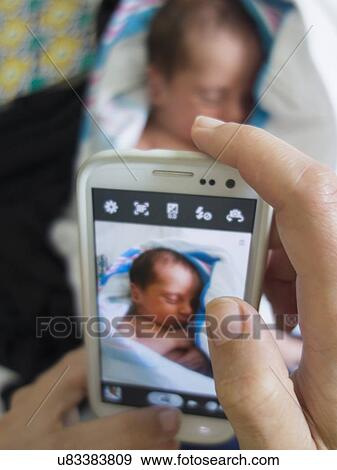 Stock Photo - Mother photographing newborn daughter. Fotosearch