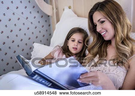 Mother reading bedtime story to her daughter (4-5) View Large Photo Image Stock Photo - Mother reading bedtime story to her daughter (4-5). Fotosearch