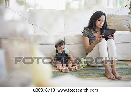 Mother using tablet pc while her son (6-11 months) playing with building blocks View Large Photo Image Stock Image - Mother using tablet pc while her son (6-11 months) playing with building blocks. Fotosearch