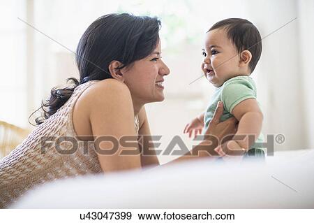 Stock Photo - Mother with her baby son (6-11 months) in bedroom. Fotosearch