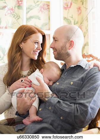 Stock Image - Parents holding their sleeping baby (2-5 months) . Fotosearch
