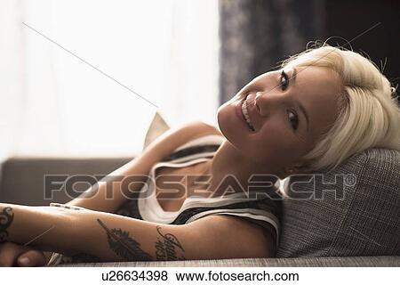 Stock Photo - Portrait of blonde woman relaxing on sofa. Fotosearch