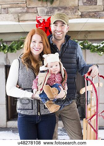 Stock Photo - Portrait of family with one child (2-5 months) and sledge. Fotosearch