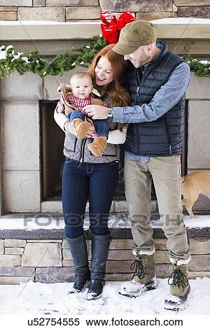 Stock Photography - Portrait of family with one child (2-5 months) in front of house. Fotosearch