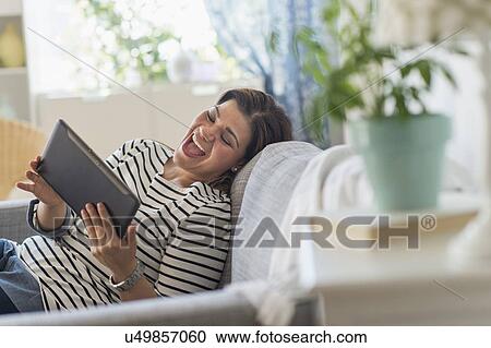 Portrait of happy woman lying on sofa with tablet pc View Large Photo Image Stock Image - Portrait of happy woman lying on sofa with tablet pc. Fotosearch