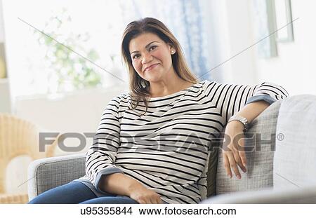 Portrait of happy woman sitting on sofa View Large Photo Image Picture - Portrait of happy woman sitting on sofa. Fotosearch