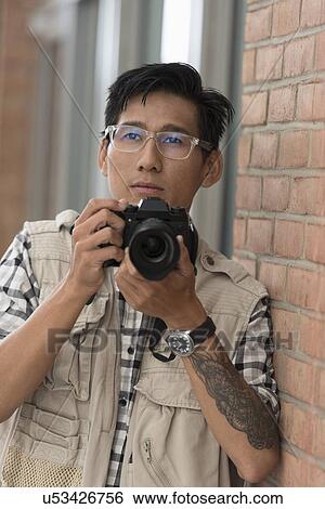 Stock Photograph - Portrait of man holding camera. Fotosearch