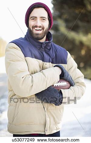 Stock Photo - Portrait of man holding football outdoors. Fotosearch