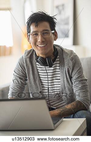 Stock Image - Portrait of man with headphones in front of laptop. Fotosearch
