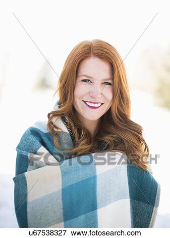 Stock Photo - Portrait of mid adult woman wrapped in checked blanket. Fotosearch
