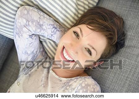 Portrait of smiling woman lying on sofa View Large Photo Image Picture - Portrait of smiling woman lying on sofa. Fotosearch