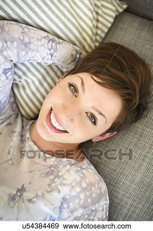 Stock Photo - Portrait of smiling woman lying on sofa. Fotosearch