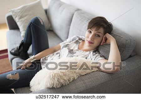Portrait of smiling woman sitting on sofa View Large Photo Image Stock Photo - Portrait of smiling woman sitting on sofa. Fotosearch