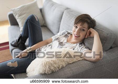 Portrait of smiling woman sitting on sofa View Large Photo Image Stock Photo - Portrait of smiling woman sitting on sofa. Fotosearch