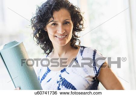Stock Photograph - Portrait of smiling woman with yoga mat. Fotosearch
