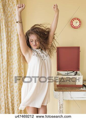Stock Image - Portrait of woman dancing happily in room. Fotosearch