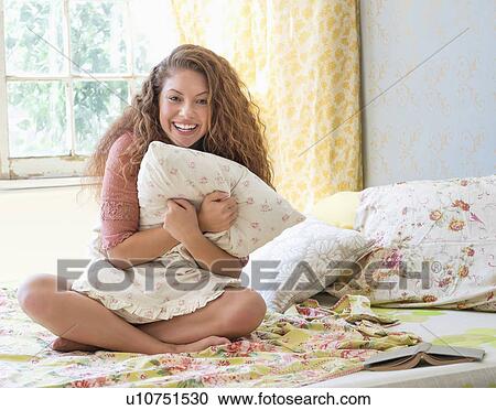Stock Image - Portrait of woman embracing pillow. Fotosearch