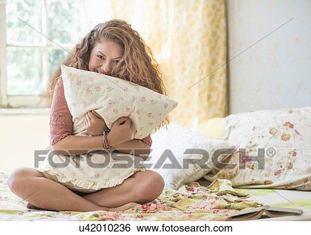 Stock Photograph - Portrait of woman embracing pillow. Fotosearch