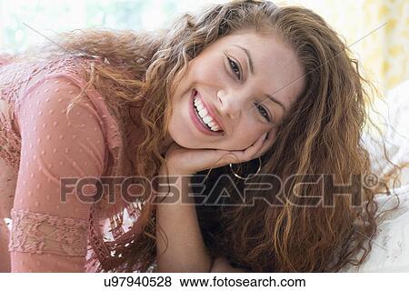 Stock Photo - Portrait of woman lying on bed. Fotosearch