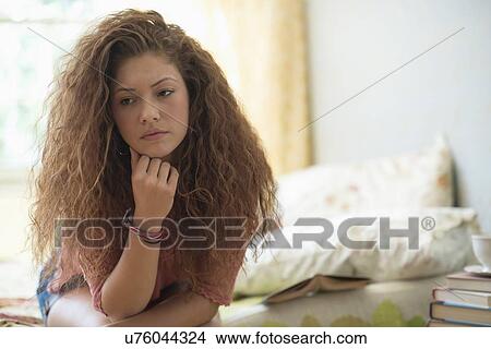 Picture - Portrait of woman sitting on bed. Fotosearch