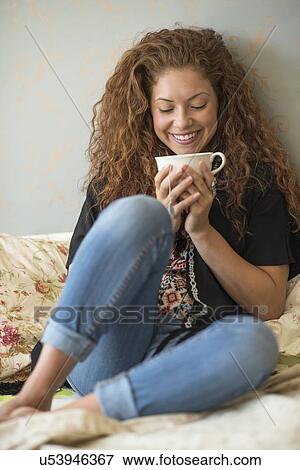 Portrait of woman sitting on bed with tea cup View Large Photo Image Stock Photo - Portrait of woman sitting on bed with tea cup. Fotosearch