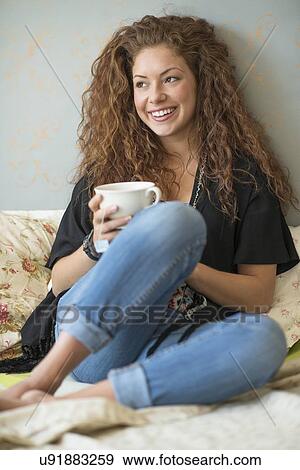Portrait of woman sitting on bed with tea cup View Large Photo Image Stock Photo - Portrait of woman sitting on bed with tea cup. Fotosearch