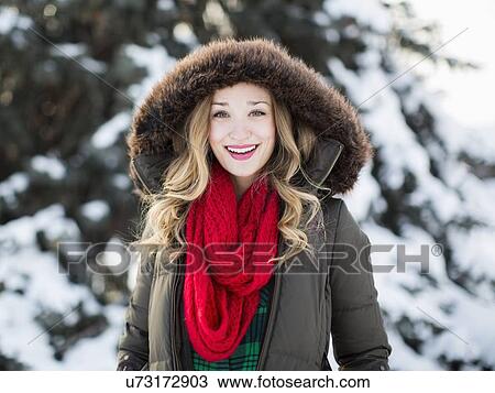 Stock Image - Portrait of woman wearing red scarf smiling outdoors. Fotosearch