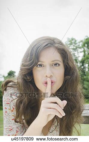Stock Photo - Portrait of woman with finger on lips. Fotosearch