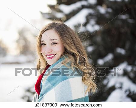 Stock Photo - Portrait of woman wrapped in blanket smiling outdoors. Fotosearch