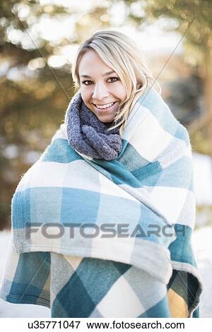 Stock Photo - Portrait of woman wrapped in blanket standing outdoors. Fotosearch