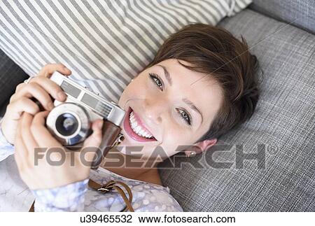 Stock Image - Portrait of young woman holding old fashioned camera. Fotosearch