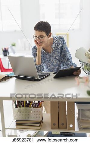Senior business woman using cell phone and tablet pc in office View Large Photo Image Stock Image - Senior business woman using cell phone and tablet pc in office. Fotosearch