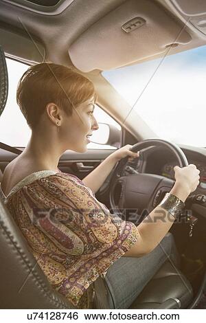 Stock Photograph - Side view of woman driving car. Fotosearch