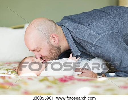 Stock Image - Studio shot of father kissing his son (2-5 months). Fotosearch